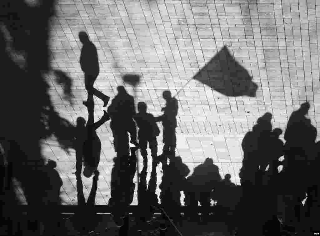 A flipped picture showing the shadows of servicemen of Kyiv-1 Battalion holding a flag as they stand guard near the Ukrainian parliament.&nbsp;(epa/Sergei Dolzhenko) 