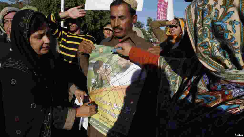 A woman from the All Pakistan Lady Health Workers Welfare Association defaces a poster that condemns the polio-eradication drive during a protest in Islamabad against the recent killings. (Reuters/Faisal Mahmood)