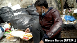 Un tânăr afgan mănâncă printre gunoaiele unei clădiri abandonate din centrul Timișoarei.