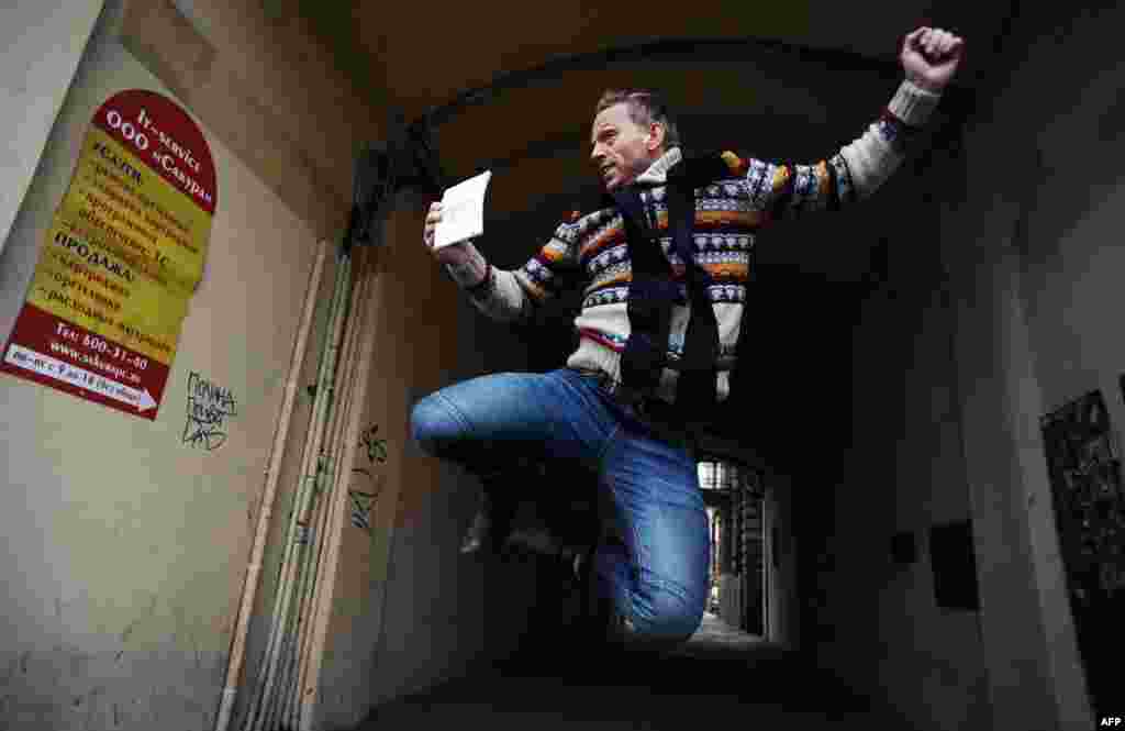 Greenpeace International Dutch activist Mannes Ubels jumps for joy with his passport and Russian transit visa in hand outside of the offices of Russia&#39;s Federal Migration Service Department in St. Petersburg. (AFP/Olga Maltseva)