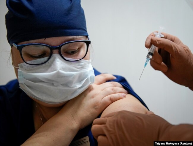 Врач получает инъекцию российской вакцины Спутник V