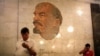 Men stand in front of a mosaic depicting former Soviet leader Vladimir Lenin at the Biblioteka Imeni Lenina metro station in Moscow.
