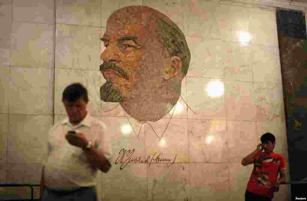 Men stand in front of a mosaic depicting former Soviet leader Vladimir Lenin at the Biblioteka Imeni Lenina metro station in Moscow.