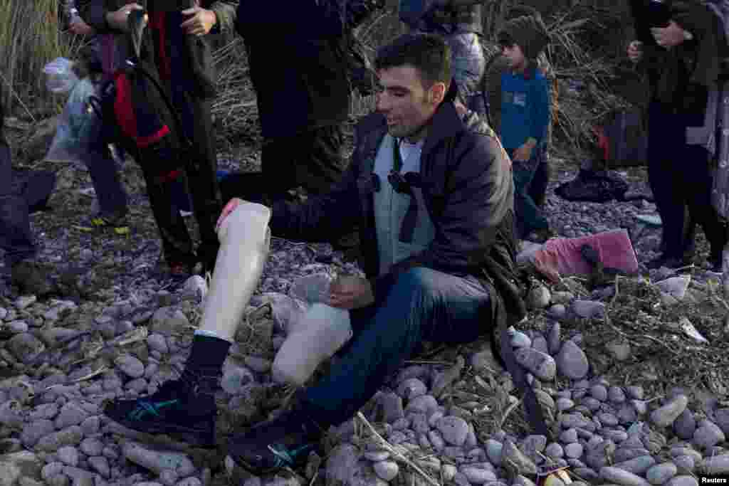 An Afghan refugee prepares to put on his prosthetic leg moments after arriving on an overcrowded dinghy on the Greek island of Lesbos, after crossing a part of the Aegean Sea from the Turkish coast. (Reuters/Dimitris Michalakis)