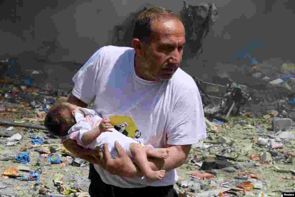 A man holds a baby that survived what activists said was a site hit by a barrel bomb dropped by Syrian government forces in the old city of Aleppo on June 3. (Reuters/Abdalrhman Ismail)