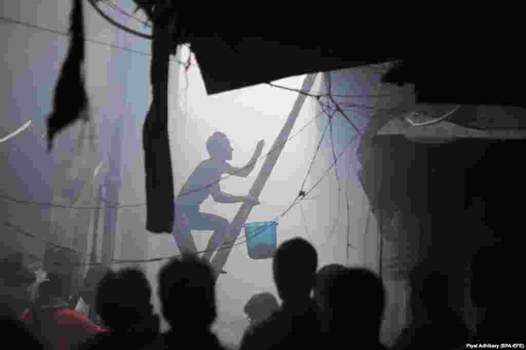 A shop owner climbs a ladder with a bucket of water as he tries to extinguish a fire that broke out at local market in Calcutta, India. The market was evacuated. Two men died in the blaze. (epa-EFE/Piyal Adhikary)