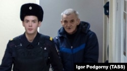 Юрій Дмитрієв (п) у супроводі поліцейського перед судом у Петрозаводську