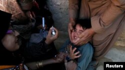 FILE: A boy reacts as he is being administered polio vaccine drops by anti-polio vaccination workers in Quetta, the capital of southwestern Balochistan province.