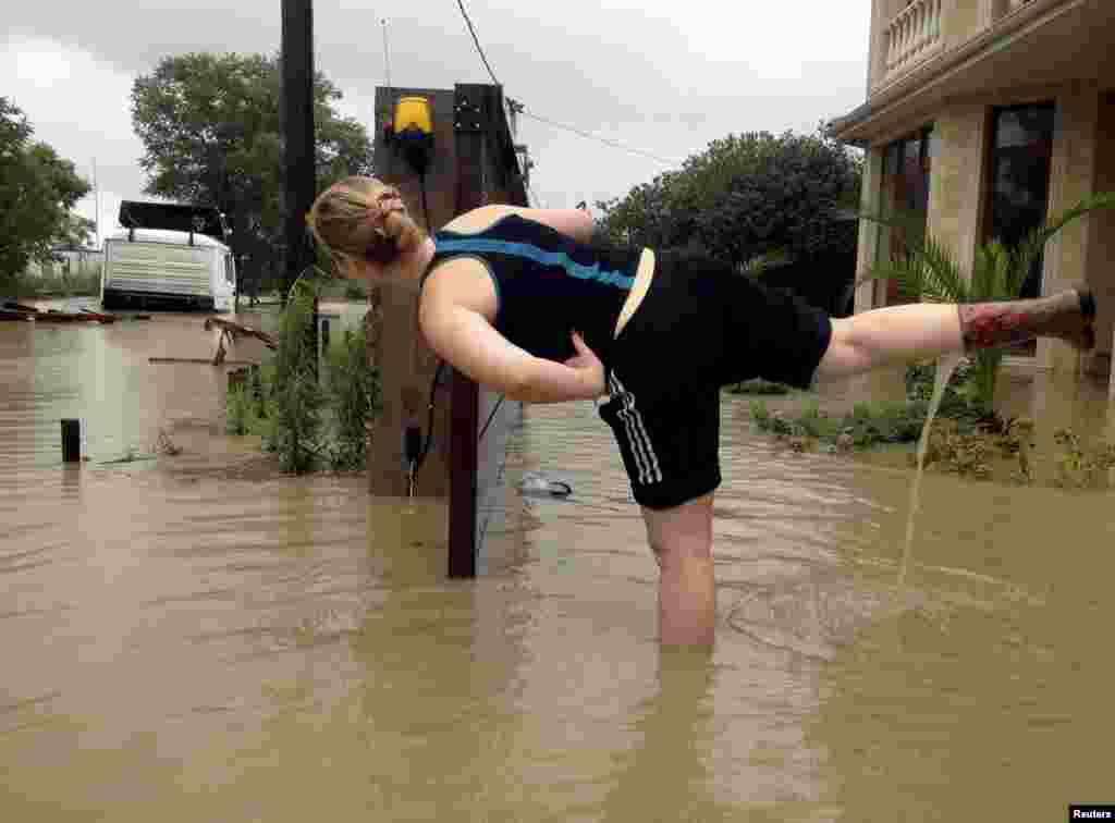 A woman stands on one leg, water pouring out of her other boot, as she looks at a partially submerged truck on a street flooded after heavy rains in Sochi, Russia, on June 25. (Reuters/​Kazbek Basaev)