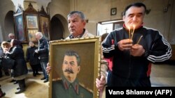Мужчина с портретом Сталина во время богослужения в Гори, 5 марта 2019 г.