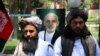 Taliban members stand in front of a portrait of Afghan President Ashraf Ghani as they attend a ceremony at the governor's office after being released, in Herat on May 26.