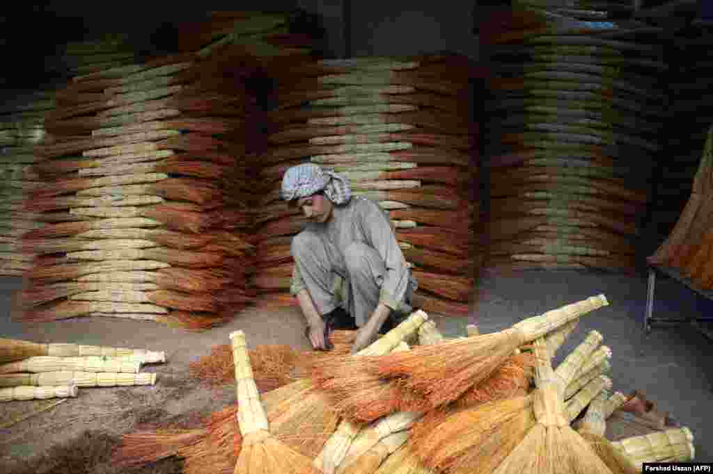 Afghan shopkeeper Naeem, 32, sorts brooms in his shop as he waits for customers on the outskirts of the northern city of Mazar-e Sharif. (AFP/Farshad Usyan)