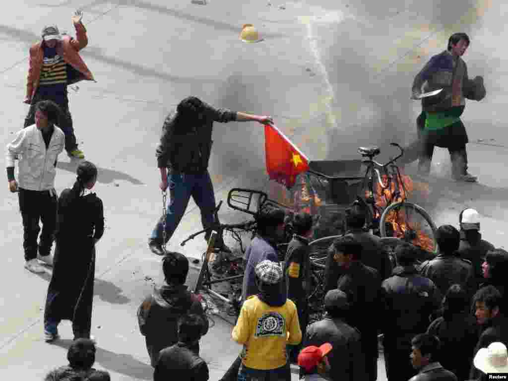 A protester burns a Chinese flag during a protest in the Tibetan capital Lhasa March 14, 2008. Protesters in Tibet's capital burnt shops and vehicles and yelled for independence on Friday as the region was hit by protests, prompting the Dalai Lama to urge Beijing to stop "brute force". REUTERS/Stringer 
