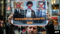 A Syrian man holds a poster of (L-R) Russian, Iranian and Syrian strongmen which reads, "Imperialist Iran get out of Syria" during a protest against the Syrian regime in Turkey- File photo