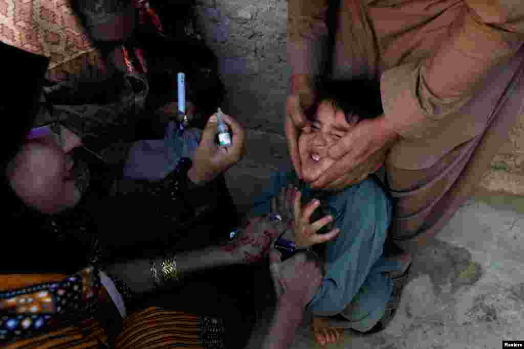 A boy reacts as he is being administered polio vaccine drops by vaccination workers along a street in Quetta, Pakistan. (Reuters/Naseer Ahmed)