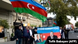 People wave the national flag and hold portraits of Azerbaijani President Ilham Aliyev and his father and predecessor Heydar as they celebrate in the streets of Baku on November 10.