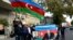 People wave the national flag and hold portraits of Azerbaijani President Ilham Aliyev and his father and predecessor Heydar as they celebrate in the streets of Baku on November 10.
