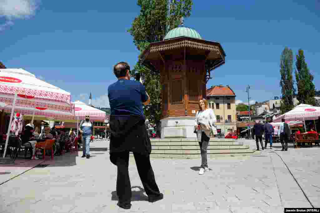 Туристы из Сербии фотографируются на фоне деревянного фонтана османской эпохи в Сараеве, столице Боснии.&nbsp;