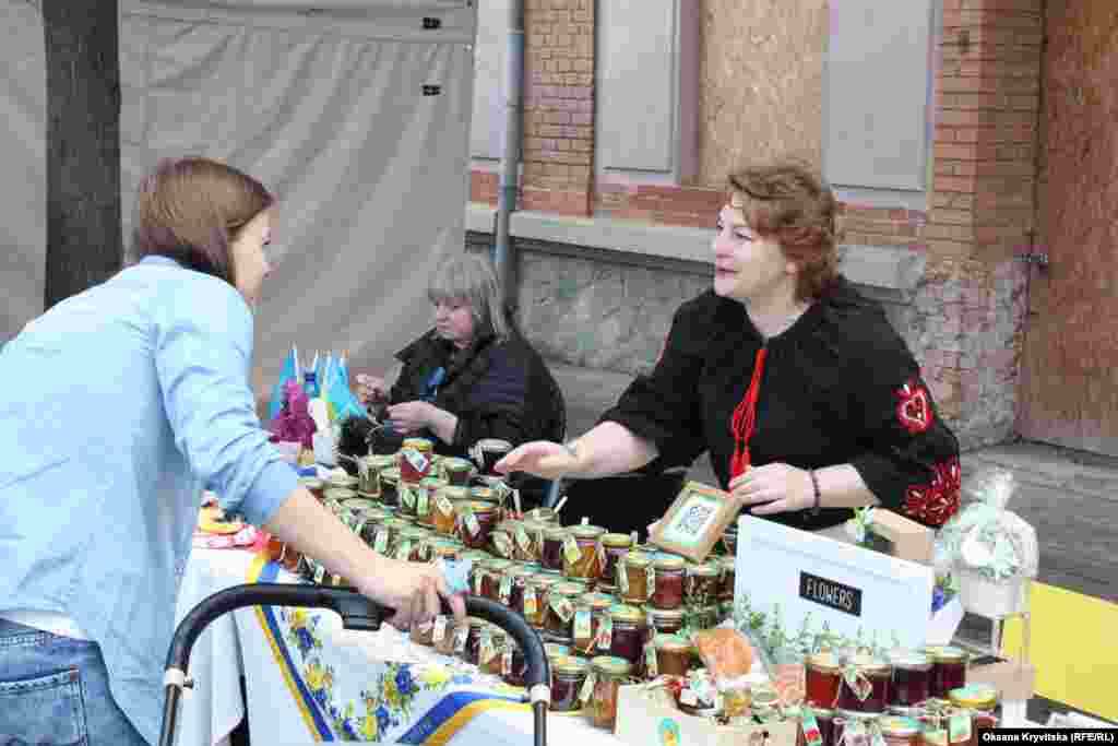 Продавчиня пропонує домашнє варення та мед відвідувачці фестивалю