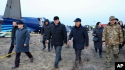 Members of an investigation committee and local officials walk past the wreckage of Azerbaijan Airlines' Flight J2-8243, which crashed in Aqtau in western Kazakhstan the previous day, killing dozens. 