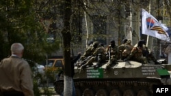 Ukraine -- Men wearing military fatigues ride on an armoured personnel carrier (APC) outside the regional state building seized by pro-Russian separatists in the eastern city of Slovyansk, April 18, 2014