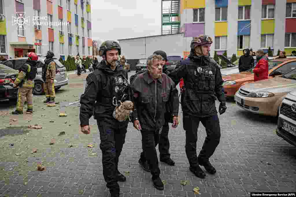 Police officers help a wounded man at the site of a Russian drone strike in Kharkiv, Ukraine.