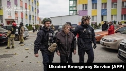 Police officers helping a wounded man at the site of a Russian drone strike in Kharkiv on November 13.