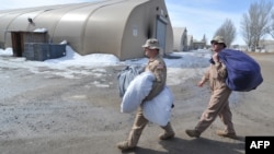 U.S. servicemen carry bags as they dismantle a tent camp at the U.S. transit center at Manas on March 6.