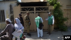 FILE: Officials from the Pakistan Bureau of Statistics collect information from a resident as Pakistani soldiers stand guard during the second phase of the national census in April.
