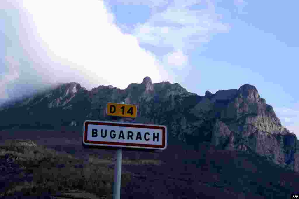 V&icirc;rful Bugarach (1231 m), din masivul Corbieres și inscripția la intrarea &icirc;n localitatea vizitată la 21 decembrie de numeroși ziariști și turiști, datorită faimei ei &icirc;n prezicerile despre &bdquo;sf&icirc;rșitul lumii&rdquo;.