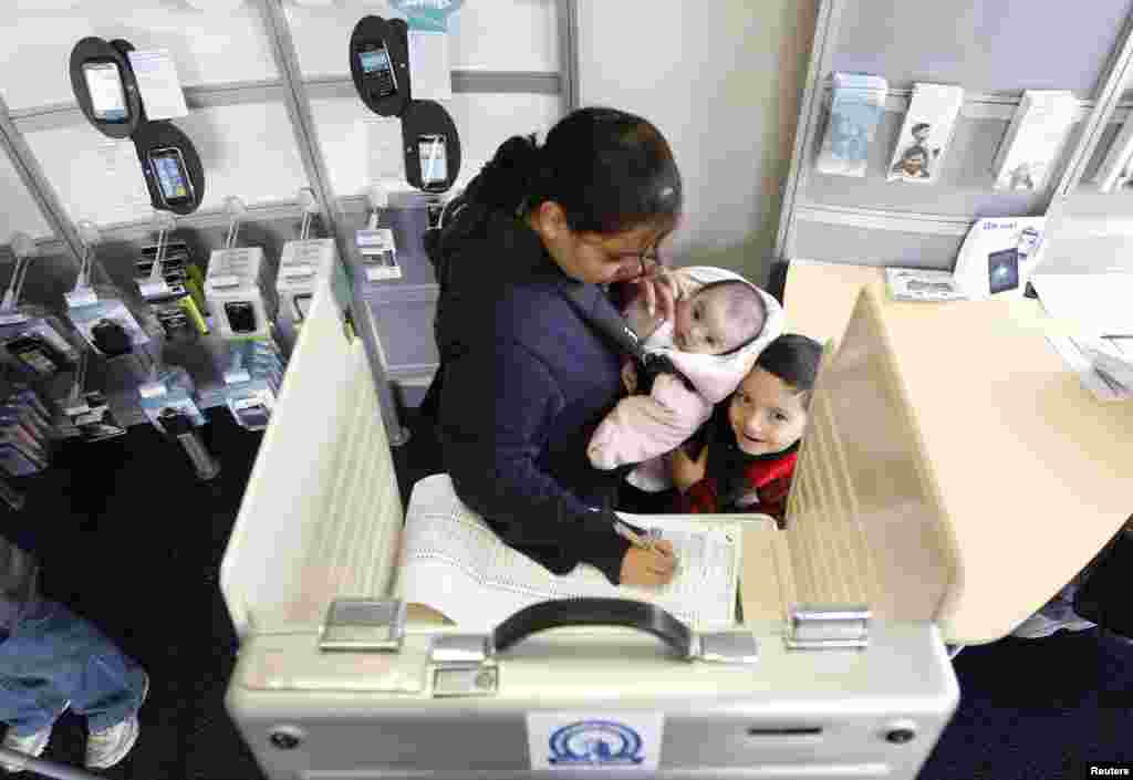 A voter casts her ballot with her two children at a polling place in a U.S. cellular store in Chicago.