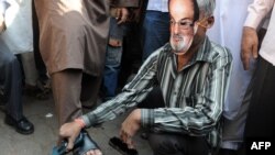 Lustragiu în Bombay, India, purtând masca lui Salman Rushdie în timpul unor proteste islamiste în care se cere moartea scriitorului, născut în acest oraș.