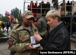 Мария Подыбайло с военным рассматривает государственную награду бойца