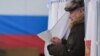 RUSSIA -- A man walks out of a voting booth at a polling station during Russia's presidential election in Moscow on March 18, 2018. 