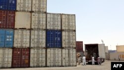 Iranian workers transfer goods from a cargo container to trucks at the port in the city of Chabahar.