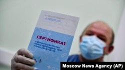 Мужчина показывает сертификат о вакцинации от коронавируса российской вакциной «Sputnik V». Москва, 28 декабря 2020 года