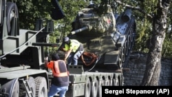Workers remove a Soviet T-34 tank installed as a monument in Narva, Estonia, on August 16.