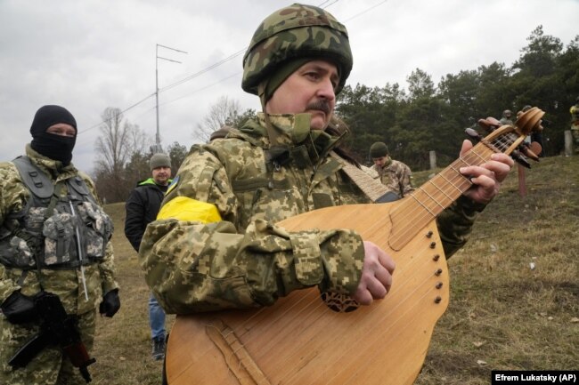 Відомий український артист Тарас Компаніченко грає на кобзі на церемонії весілля військовослужбовців ЗСУ Лесі Іващенко та Валерія Філимонова на блокпосту в Києві, 6 березня 2022 року