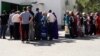 People wait in front of food stores in Ashgabat for their turn to buy basic staples at subsidized prices.