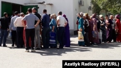 People wait in front of food stores in Ashgabat for their turn to buy basic staples at subsidized prices.