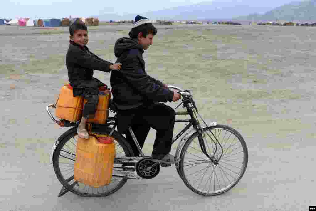 Afghan refugees, who have voluntarily returned home from neighboring Pakistan, ride a cycle near their temporary shelters in Laghman Province. (epa/Ghullamullah Habibi)