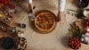 A pizza is being cut on a table by the chef.