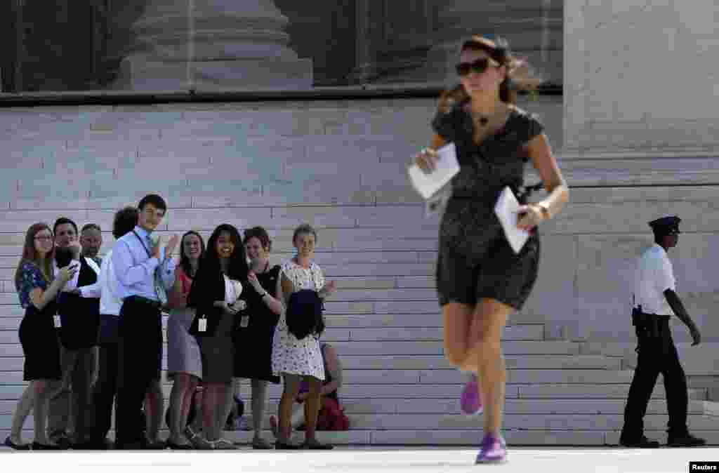 Onlookers applaud as a news assistant sprints out of the Supreme Court to deliver copies of the court&#39;s rulings to news crews outside the court building in Washington. (Reuters/Jonathan Ernst)