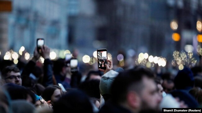 Сторонники Алексея Навального держат мобильные телефоны с включенным светом во время митинга в Москве, 21 апреля 2021 года