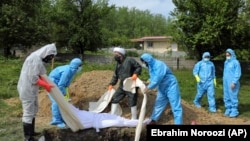 People wearing protective gear attend the funeral of a victim who died from the new coronavirus, at a cemetery in the outskirts of the city of Ghaemshahr in north of Iran, May 1, 2020