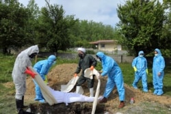 Люди в захисному спорядженні ховають померлих від коронавірусу на околиці міста Гемшахр на півночі Ірану. 1 травня 2020 року