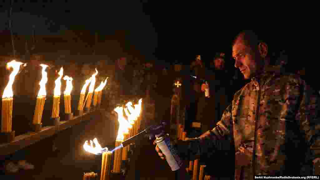 Un bărbat aprinde lumânări în piața centrală a orașului părăsit Prîpeat.