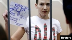 Russia -- Ukrainian army pilot Nadia Savchenko holds a sign inside a defendants' cage as she attends a hearing at the Basmanny district court in Moscow, February 10, 2015