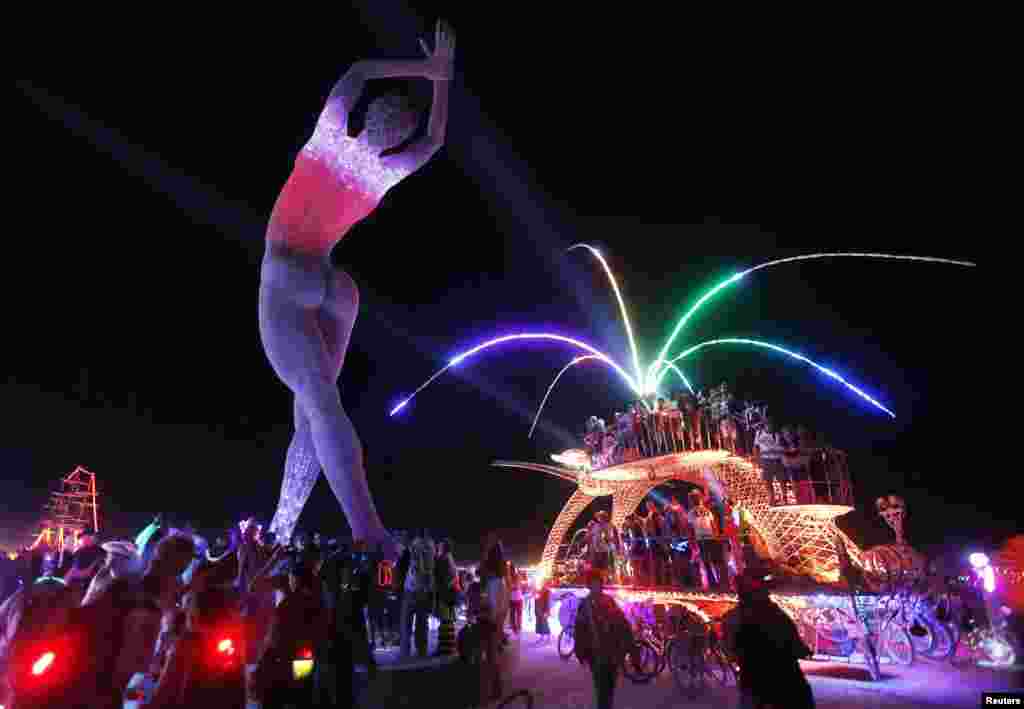 Participants dance on top of a car parked beside the &quot;Truth is Beauty&quot; sculpture, created by Marco Cochrane, at the Burning Man arts and music festival in Nevada.