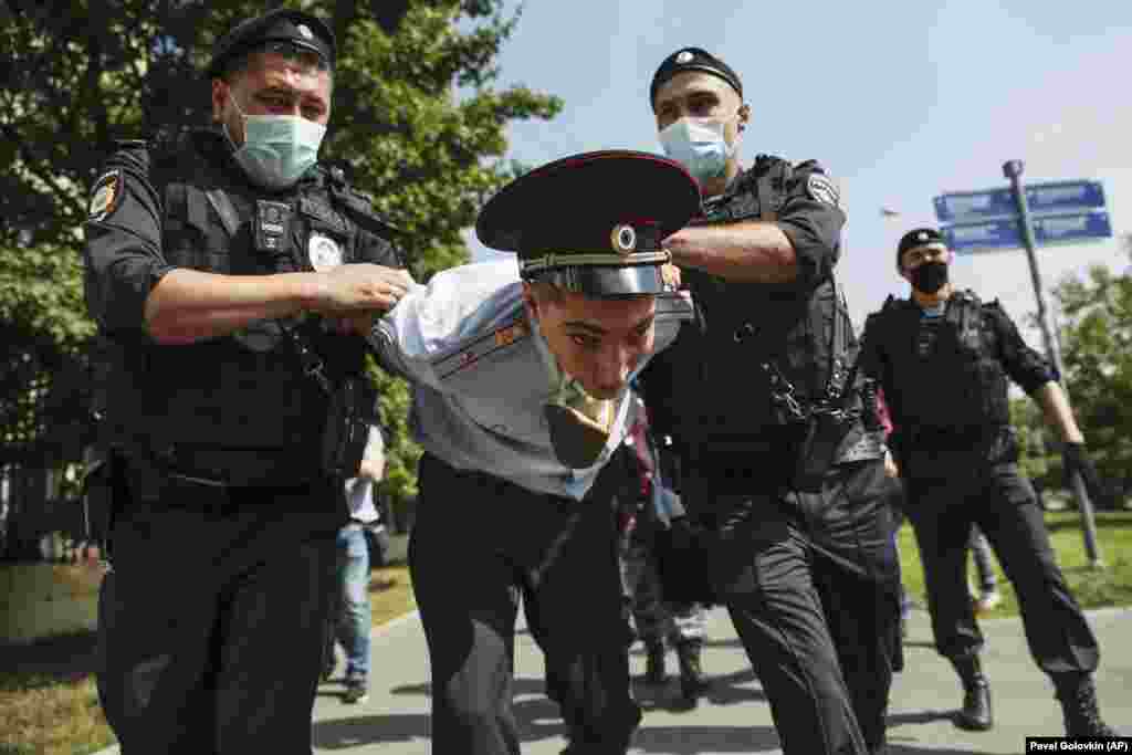 Police officers detain a protester dressed as a police officer before a court hearing of the New Greatness group, which is charged with organizing an extremist association in Russia. (AP/Pavel Golovkin) &nbsp;